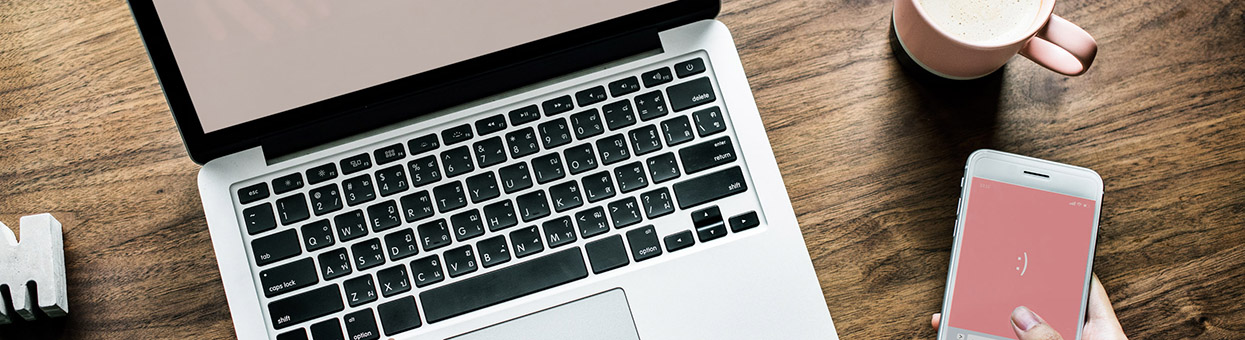 Aerial view of woman using computer laptop and a smartphone on wooden table