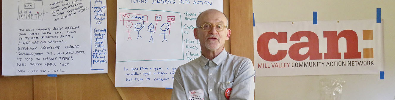 Man standing in front of posters with hand-written information for the Mill Valley Community Action Network