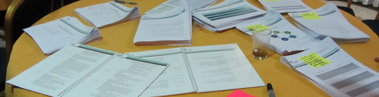 Various piles of handouts on a table with a mustard yellow tablecloth
